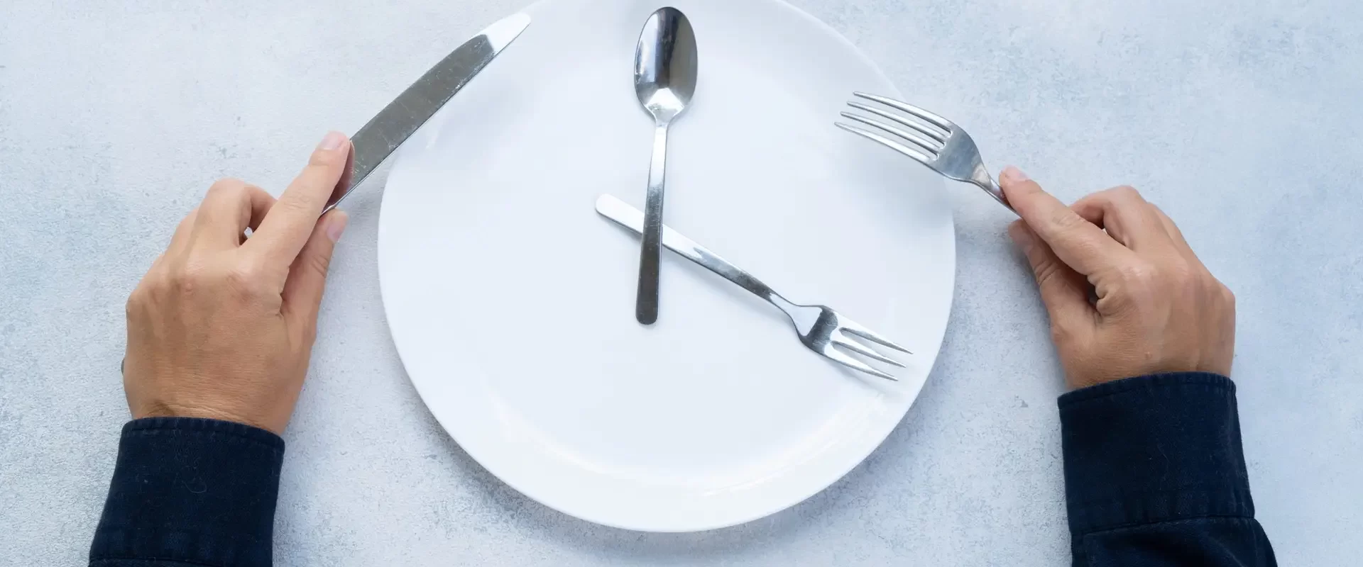 Intermitted farsting diet concept - empty plate and hands with fork and knife