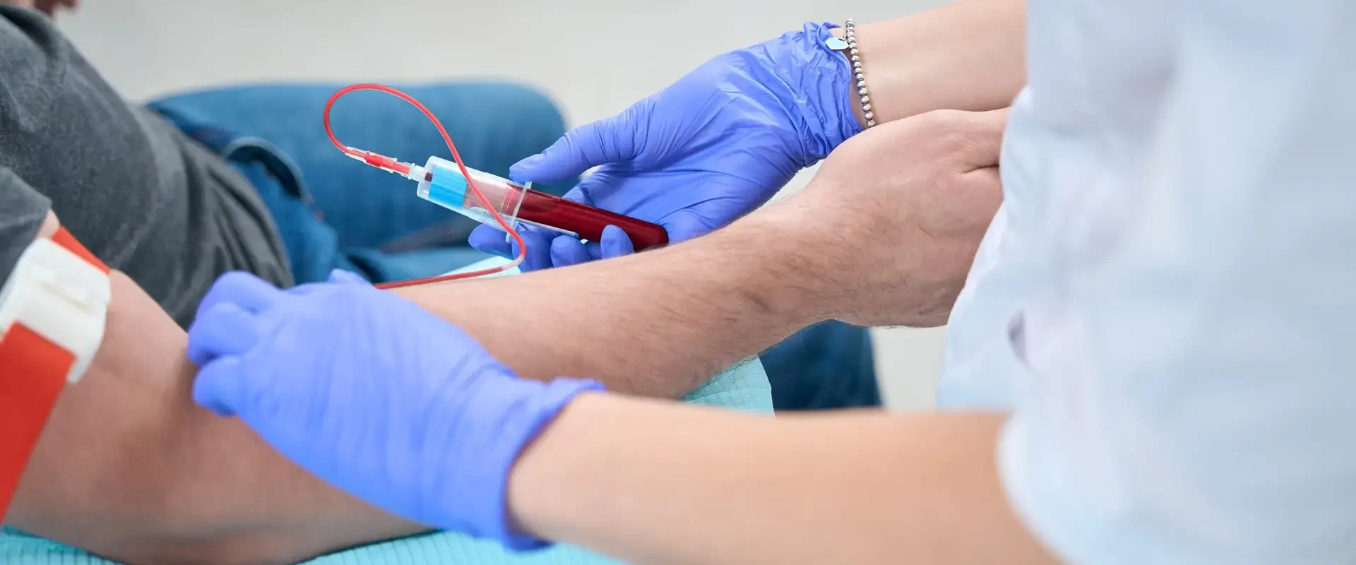 Nurse takes a blood sample from a patient in a medical clinic, she works in protective gloves